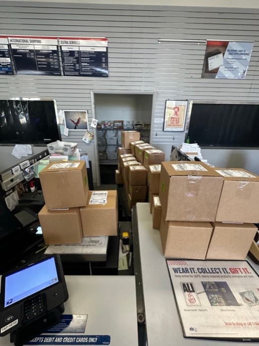 About fifteen parcels of live fish stacked on the counter of a USPS branch at handover